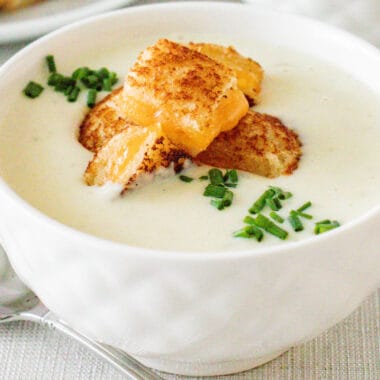 square image of a bowl of cauliflower bisque with grilled cheese croutons