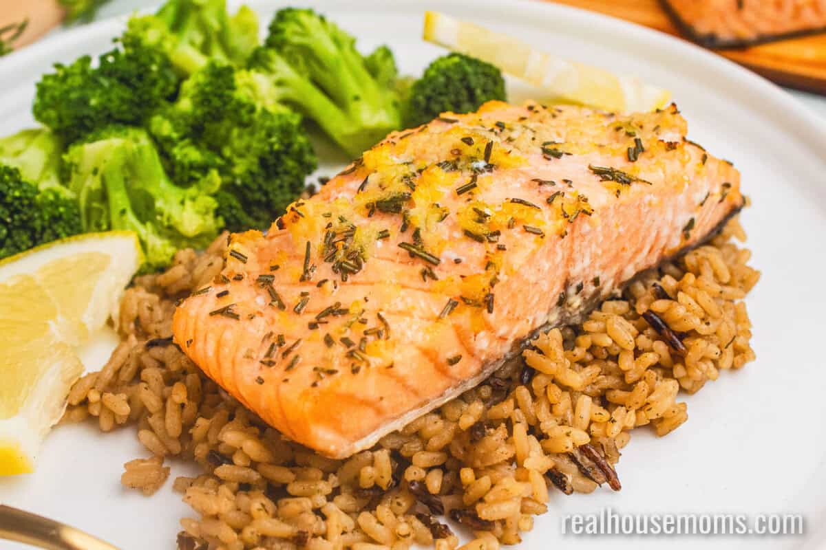 cedar plank salmon fillet served over brown rice with broccoli and lemon slices on a plate