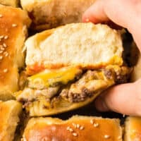 square image of a cheeseburger slider being taken from the pan
