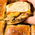 square image of a hand taking a cheeseburger slider from the pan