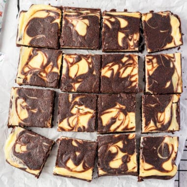 square image of cheesecake brownies on parchment paper after being cut into squares