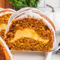 square image of a slice of cheesecake filled pumpkin bundt cake on a cake server