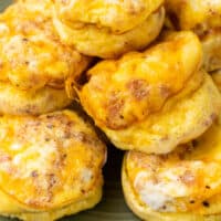 cheesy bacon & egg muffins stacked on a plate with recipe name at the bottom