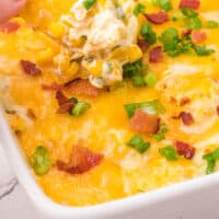 tortilla chip dipped into cheesy bacon & roasted corn dip with recipe name at the bottom