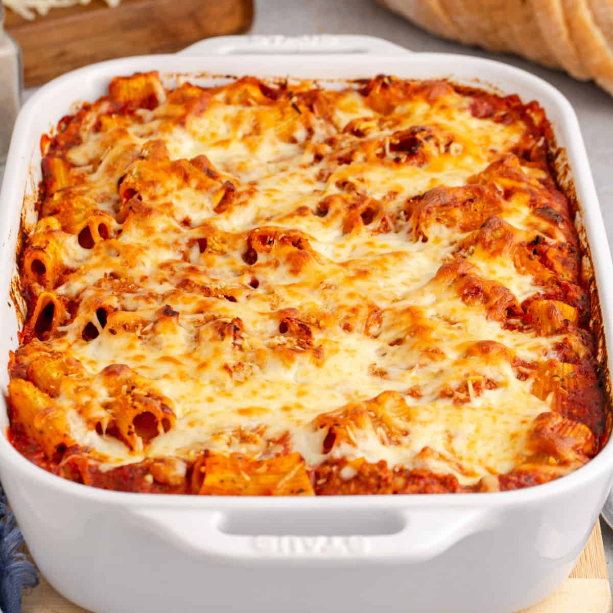 square image of cheesy baked rigatoni in a baking dish after cooking