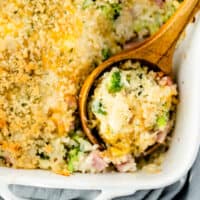 close up cheesy broccoli ham casserole in a dish with wooden spoon with recipe name at bottom