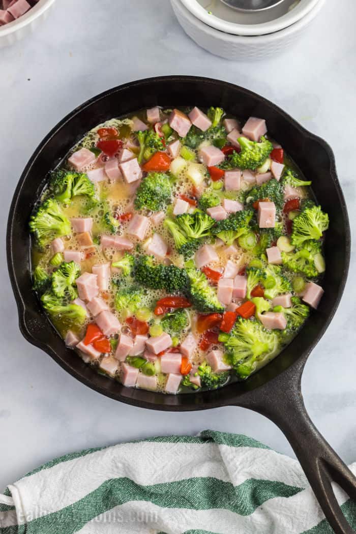 beaten eggs, ham, broccoli, and peppers in a skillet