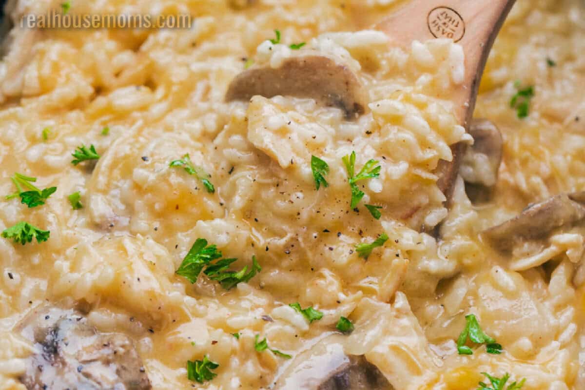 wooden spoon getting a scoop of Cheesy Crock Pot Chicken and Rice from the slow cooker