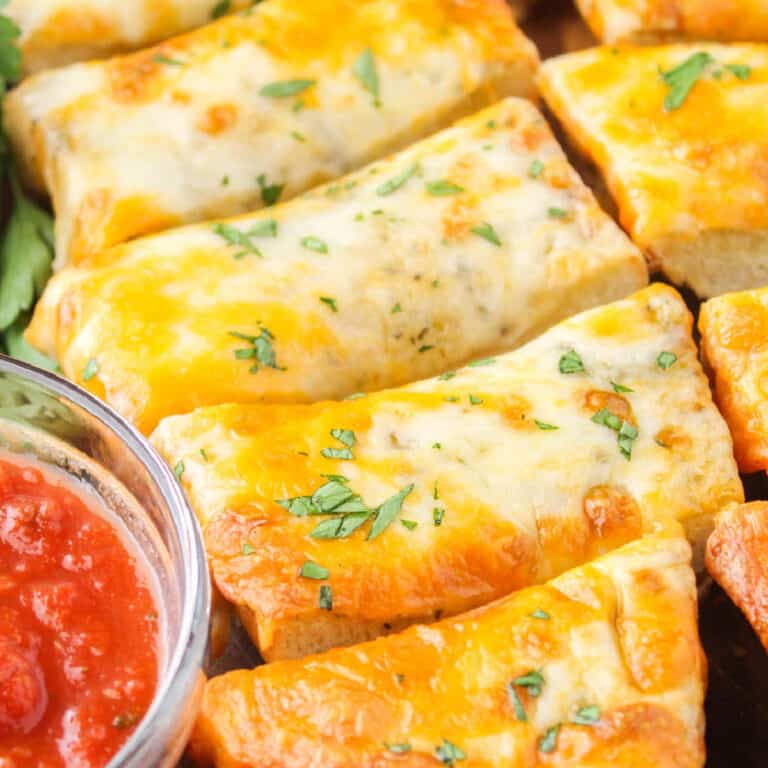 square close up image of cheesy garlic bread cut into pieces