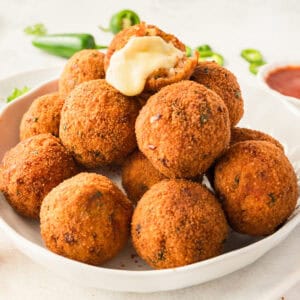 square image of a pile of cheesy mexican rice balls with the top one broken open