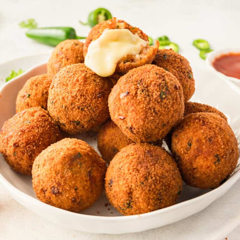 square image of a pile of cheesy mexican rice balls with the top one broken open