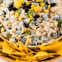 cheesy roasted corn and black bean dip in a bowl surrounded by tortilla chips with recipe name at the bottom
