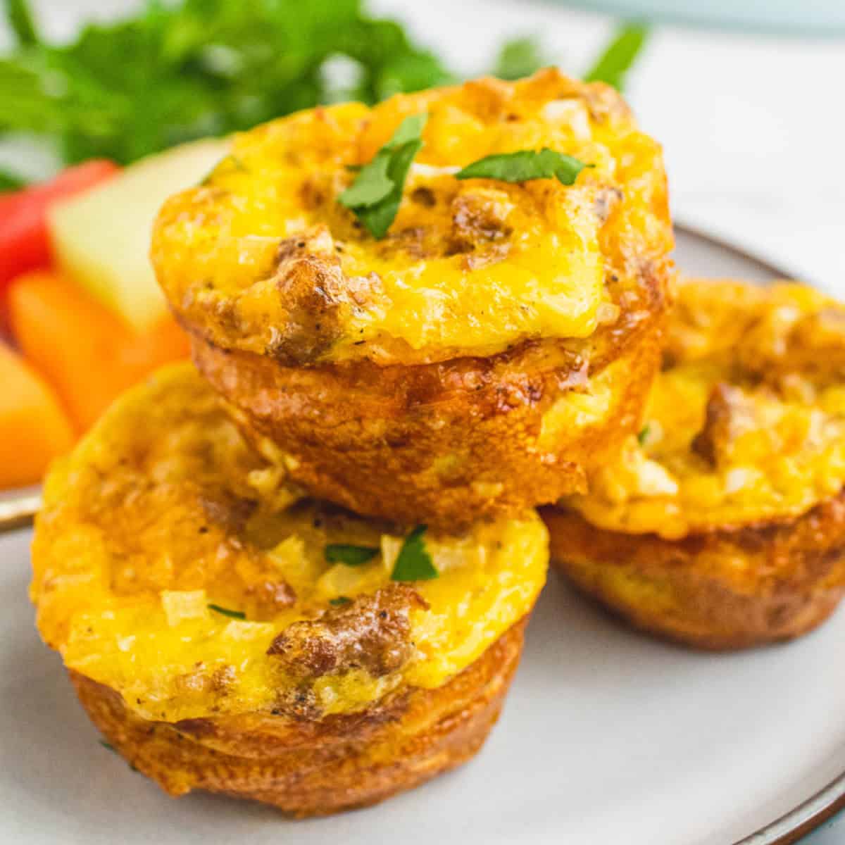 square image of three cheesy sausage hash brown egg cups on a plate