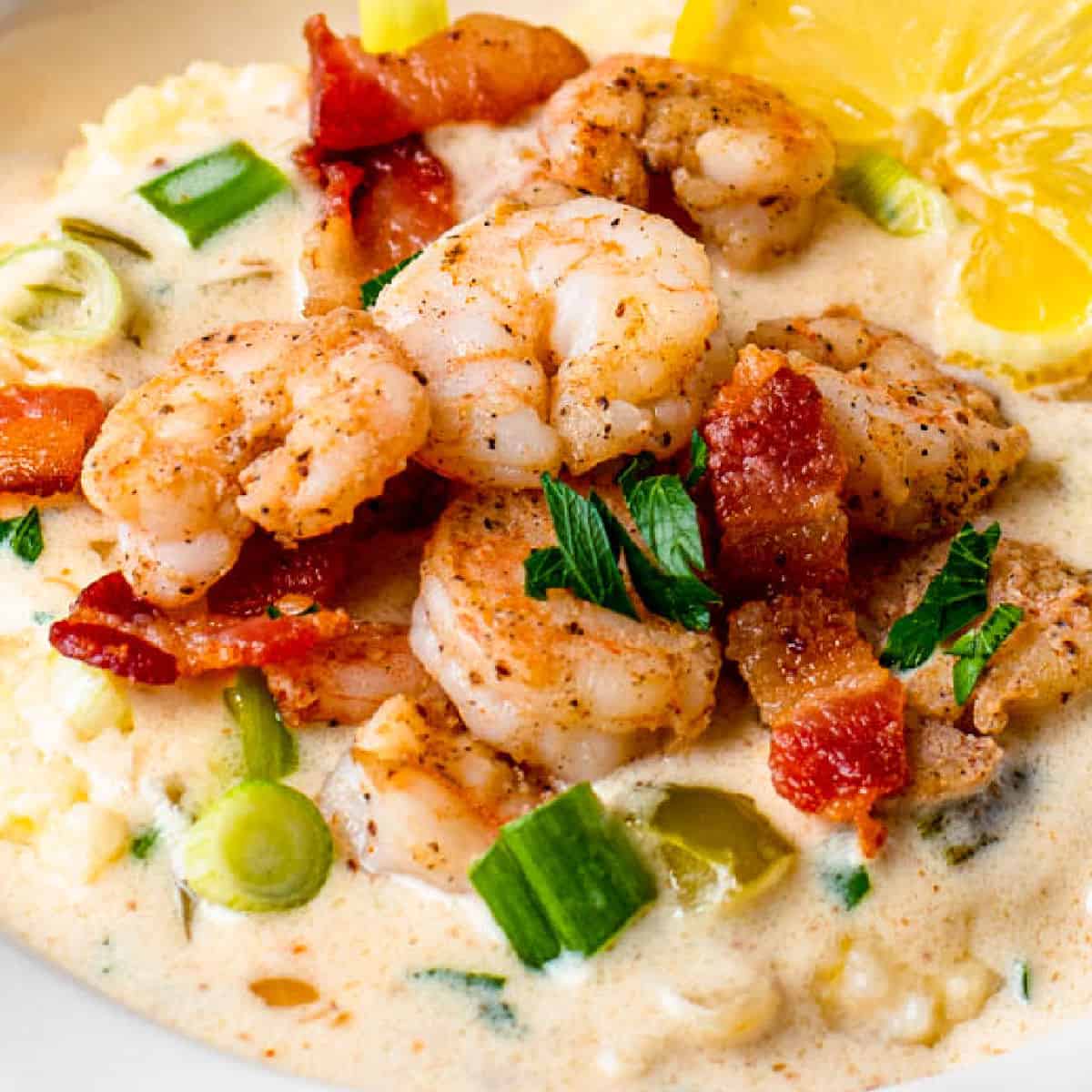 square image of shrimp and cheesy grits in a bowl with chopped green onion