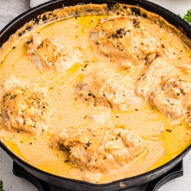square image of cheesy skillet ranch chicken thighs in a cast iron skillet