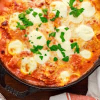 cheesy skillet ravioli bake topped with parsley with recipe name at the bottom