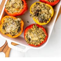 looking down at cheesy spinach and artichoke quinoa stuffed peppers in a baking dish with recipe name at the bottom