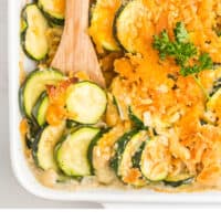 cheesy zucchini gratin in a baking dish with a wooden spoon with recipe name at the bottom
