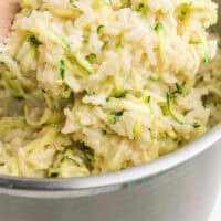 spoonful of cheesy zucchini rice over the pot with recipe name at the bottom