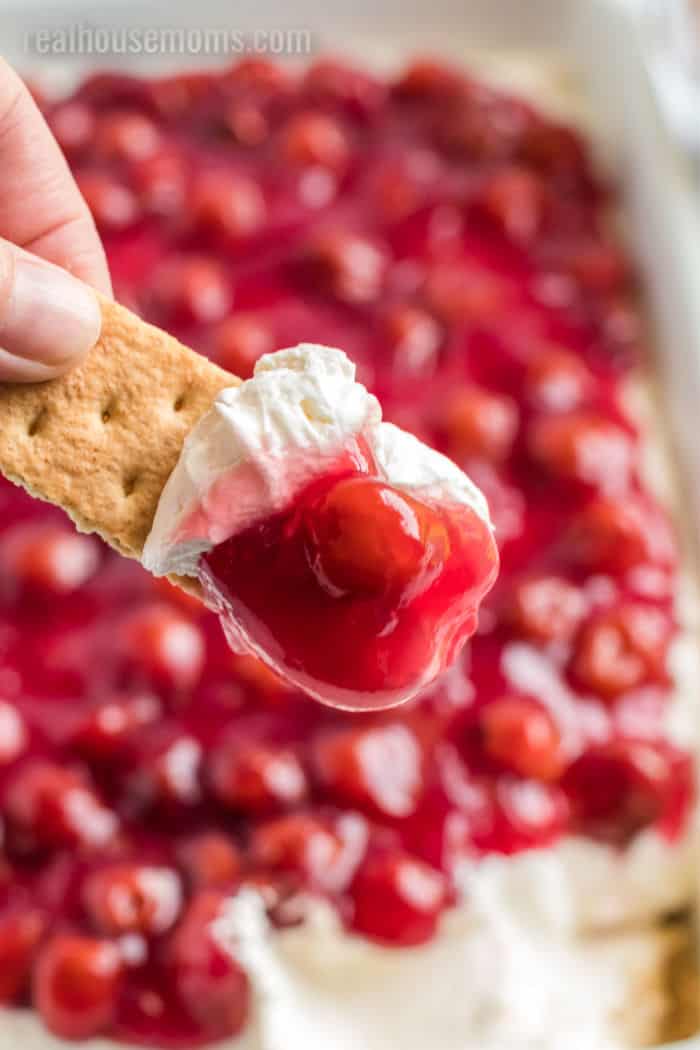 graham cracker dipped in cheesecake dip with cherry pie filling