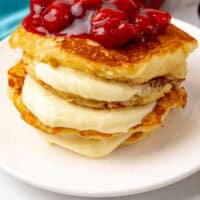 stack of cherry cheesecake pancakes on a plate with recipe name at the bottom