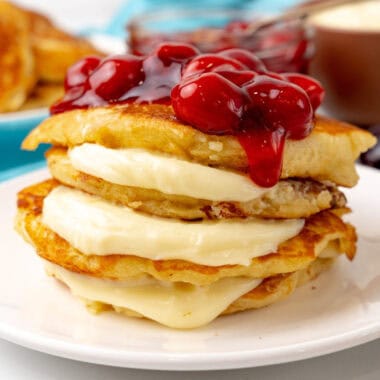 square image of a stack of cherry cheesecake pancakes on a plate