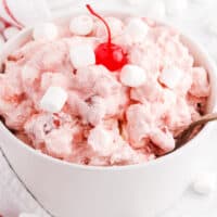 square image of cherry cheesecake salad in a bowl with a cherry on top