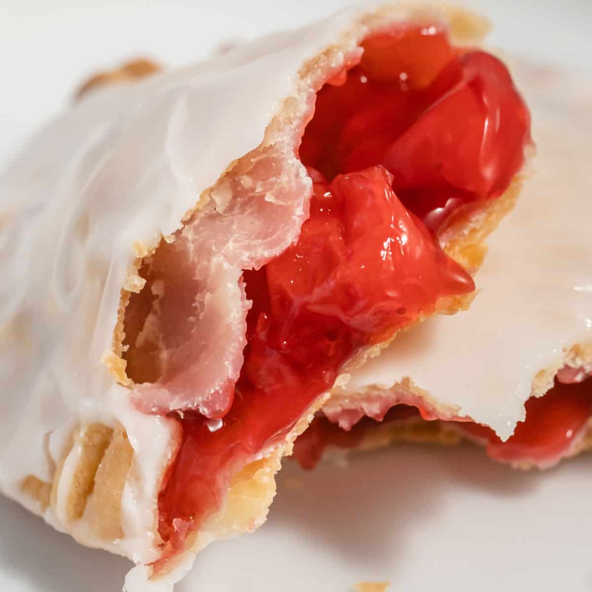 square image of cherry hand pie broken in half to shown filling