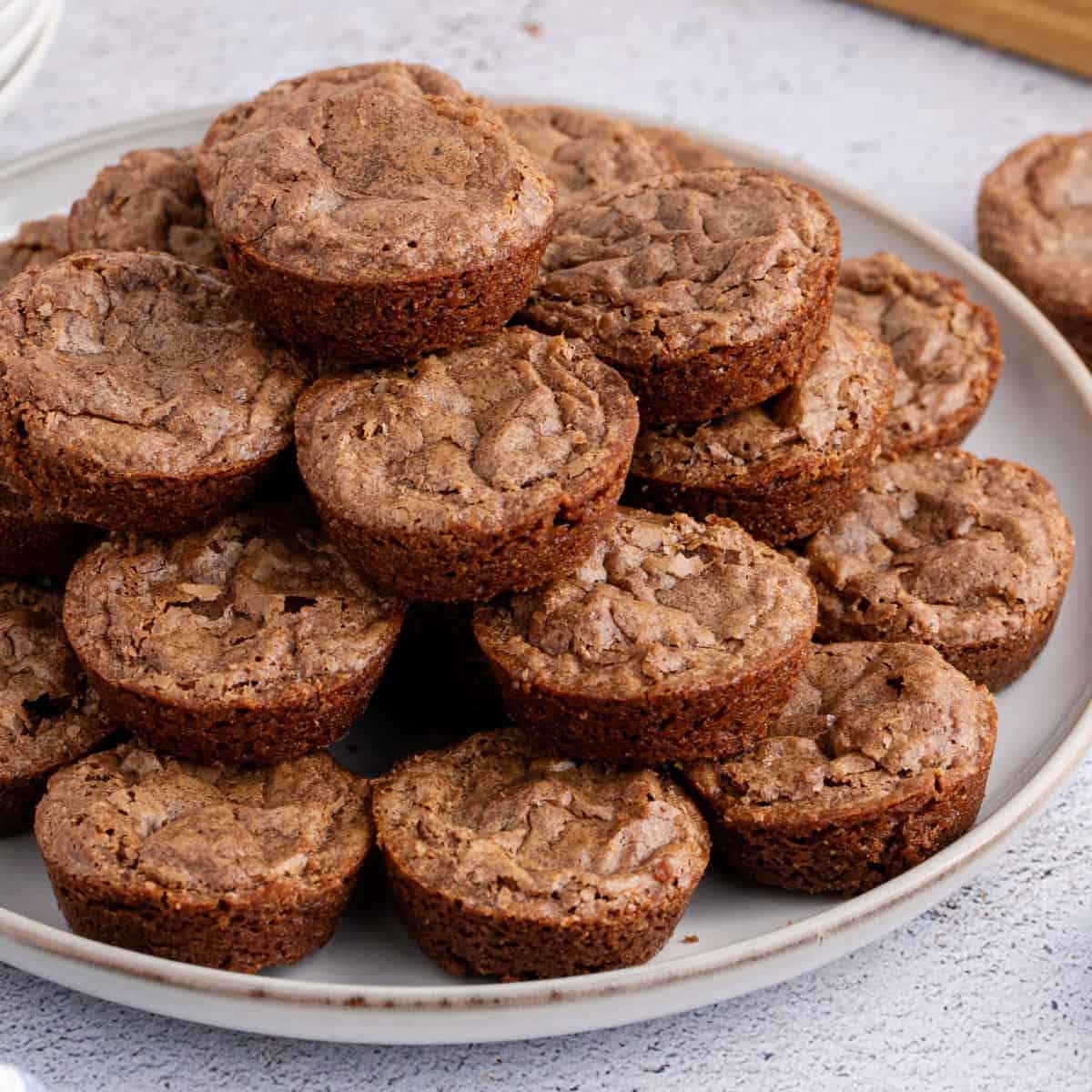 square image of chewy brownie bites stacked on a palte