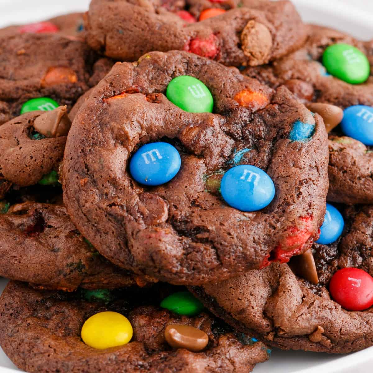 square image of cake mix chocolate M&M cookies piled on a plate