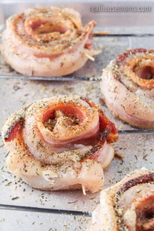 bacon chicken roll ups on metal skewers ready to cook