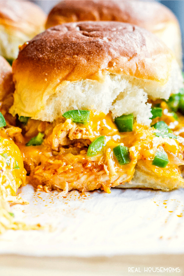 Close up of a chicken enchilada slider with green onions and a golden brown bun