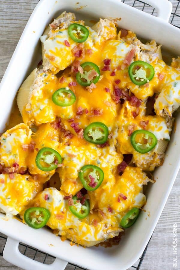 Chicken Jalapeno Popper Stuffed Shells in the pan after baking topped with jalapeno rings and crumbled bacon