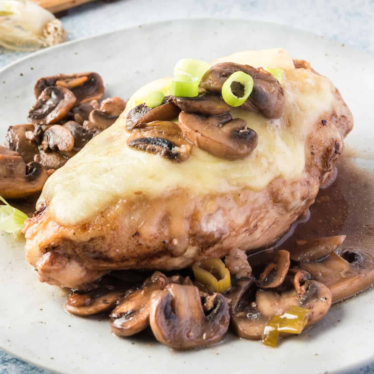 square image of chicken lombardy on a plate with mushrooms and marsala wine sauce
