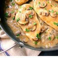 chicken marasala in a skillet coated in marsala wine sauce and mushrooms