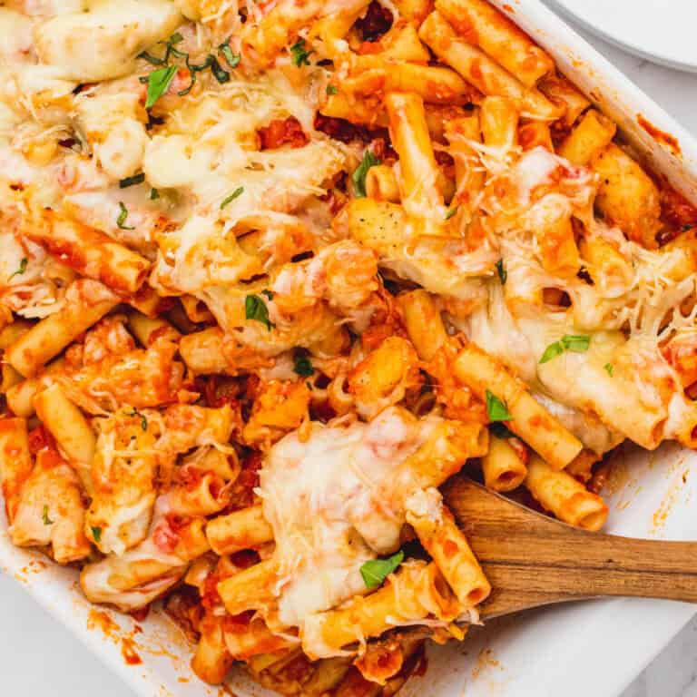square image of chicken parmesan baked ziti in a dish with with a portion on a wooden spoon