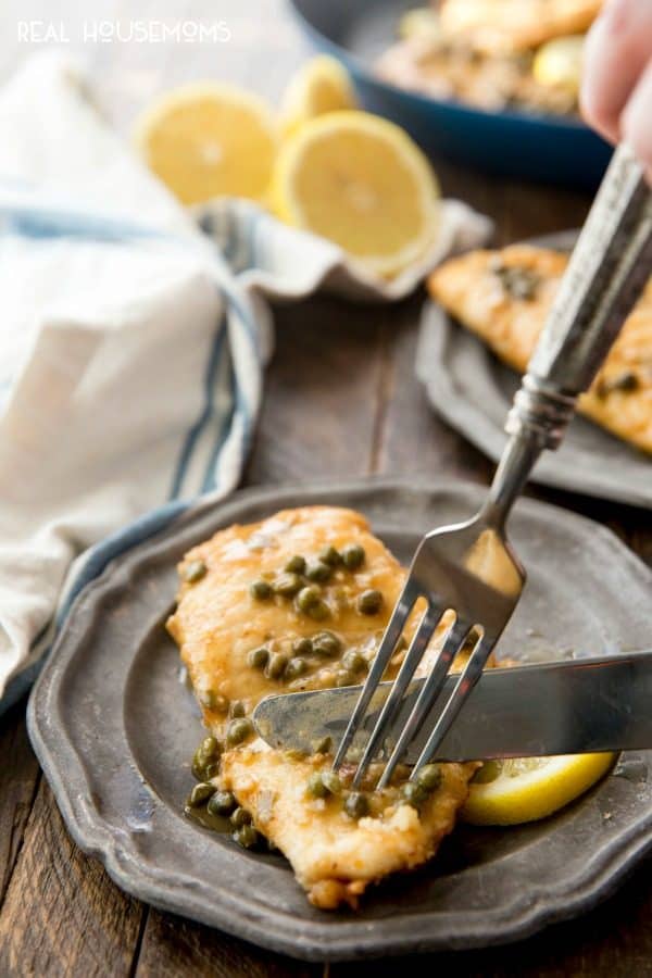 Cutting into Chicken Piccata with a fork and knife
