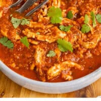 chicken tinga in a serving bowl topped with cilantro with recipe name at the bottom