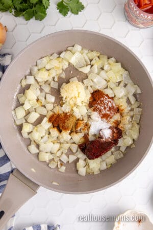 chipotle pepper, seasonings, and garlic added to sautéed onions in a large skillet