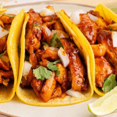 close up image of three chicken al pastor tacos on a plate