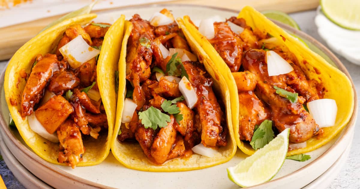 close up image of three chicken al pastor tacos on a plate