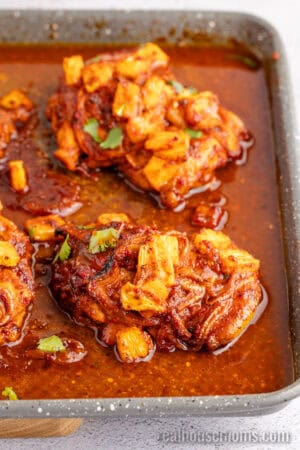 angled view of cooked chicken al pastor topped with chopped cilantro on a baking sheet