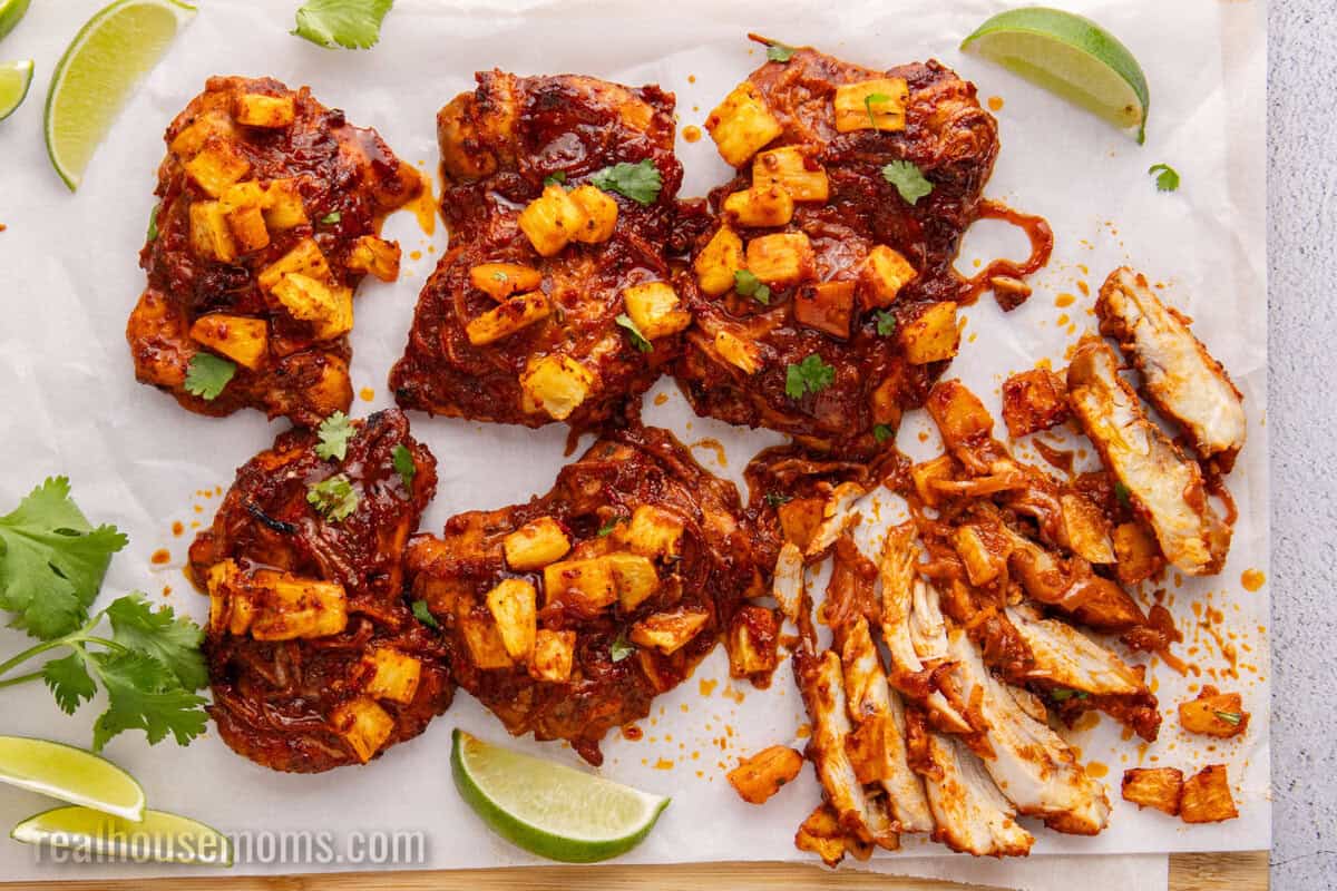 chicken al pastor on a cutting board with one thigh cut into strips