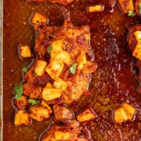 baked chicken al pastor topped with chopped cilantro on a baking sheet with the title of the post on top of the image in blue and black lettering
