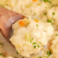 dumpling from a pot of chicken and dumplings on a wooden spoon over the soup with the title of the post on top of the image in pink and black lettering