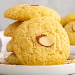 square image of a chinese almond cookie leaning on a stack of cookies on a plate