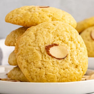 square image of a chinese almond cookie leaning on a stack of cookies on a plate