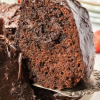 slice of chocolate bundt cake on a cake server being lifted from the plate with the title of the post on top of the image in red and black lettering