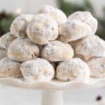 square image of chocolate chip snowball cookies piled up on a cake stand