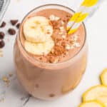 square image of chocolate peanut butter banana smoothie with banana slices, oats, and cocoa powder on top